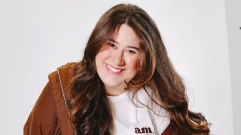 Adela Rokytova Adela Rokytova has brown wavy hair, a bright smile and she is wearing a white t-shirt with a light brown jacket. 
