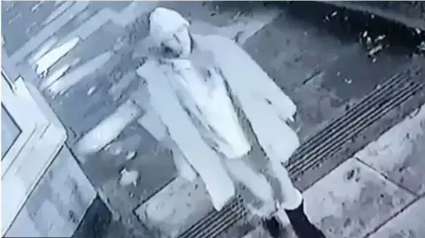 Cleveland Police Grainy black and white CCTV footage showed Ms Jenkins wearing a white hat shortly before midnight on 10 December. She is walking along a pavement close to houses.