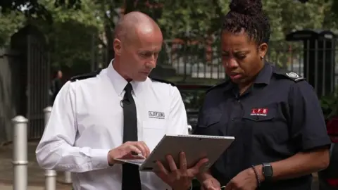 BBC London Two fire brigade staff looking at a laptop 