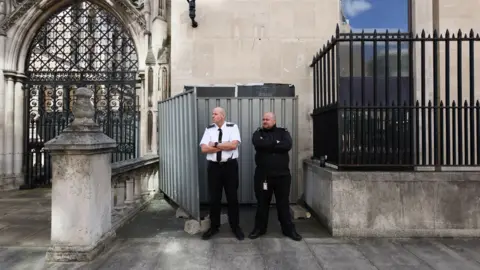 Reuters Two uniformed security men stood with their arms folded in front of steel panels, which hide the Banksy mural.