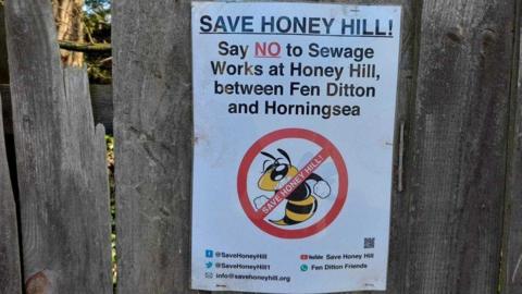 Sign on wooden fence opposing sewage works plans and saying Save Honey Hill