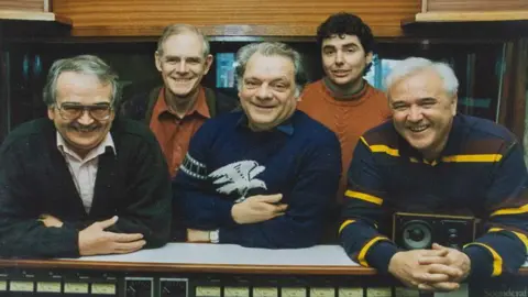 Jason Lock Group picture featuring (left to right) Brian Cosgrove, David Jason and Mark Hall smiling and leaning on a production studiodeck. Two other unidentified men stand behind smiling.