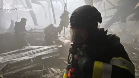 A firefighter wearing a mask inside a damaged building