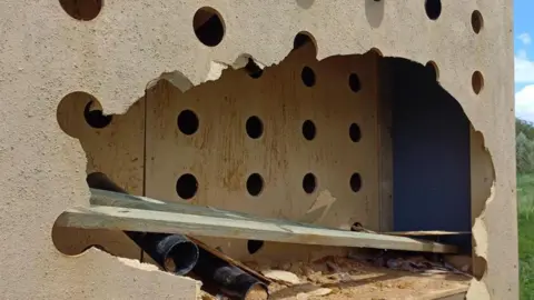 Northamptonshire Police A big nesting box with lots of holes and tubes is damaged - a panel has been smashed through and disheveled black tubes rest on the bottom of the box.