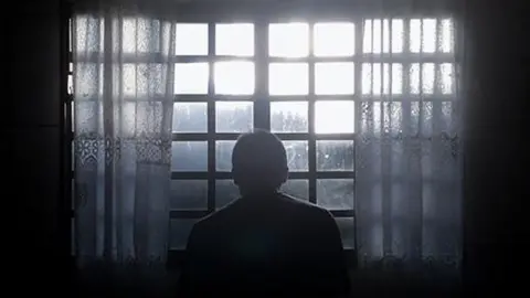 Supplied Generic image of a man sitting at a window in the dark