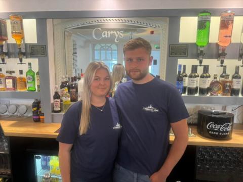 Landlords Will and Abbie standing in front of the bar