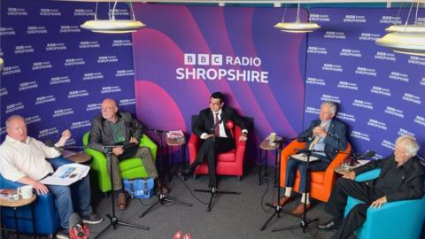 Candidates in the Wrekin constituency in coloured chairs in front of a BBC Radio Shropshire-branded backdrop