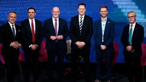 Getty Images The leaders of Scotland's six largest political parties standing in a row - from left, Alex Cole-Hamilton, a man with greying hair in a dark suit and tie, Anas Sarwar, a man with black hair in a dark suit and red tie, John Swinney, a bald man with glasses in a dark suit and purple tie, Russell Findlay, a man with black hair in a dark suit and stripy blue tie, Ross Greer, a man with red hair and glasses in a dark suit with no tie, and Malcolm Offord, a man with grey hair and glasses wearing a dark suit with an aquamarine tie.