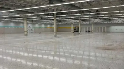 Acorn Property Group A huge empty space with a shiny grey tiled floor and stark empty walls. 