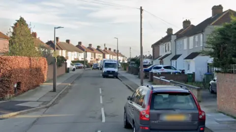 General view of  Dunwich Road which has houses along it with cars parked in driveways and on the road.