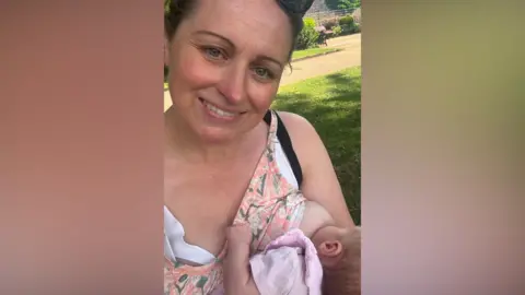Supplied A woman breastfeeding her baby in a park 