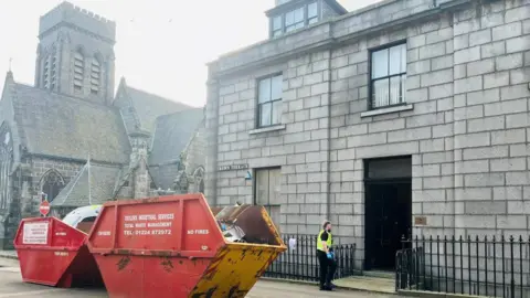 A police officer wearing blue rubber gloves outside a property in Aberdeen