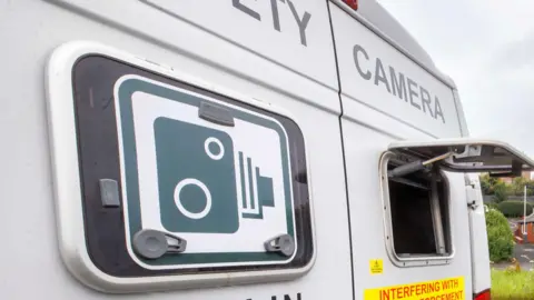 PA A generic speed camera van with a hatch in the right hand back door where the camera is located. On the left back door is a black and white speed camera sign.