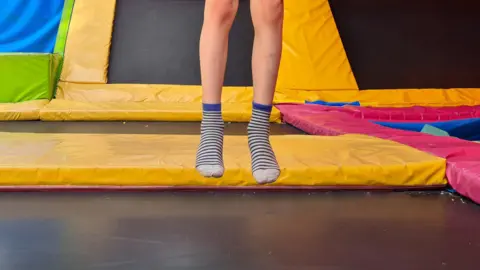 A child's legs bouncing on a trampoline