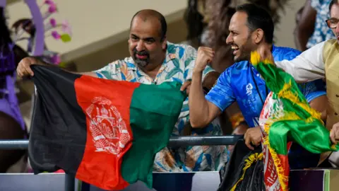 Getty Images Fans cheer on Afghanistan's cricket team as they beat Australia 