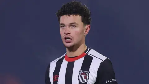 George McEachran, wearing Grimsby Town's black and white striped home shirt with a red trim on the collar, while in action for the Mariners in 2026