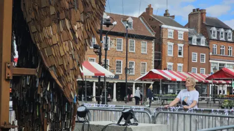 Adele stares up at the statue from the market place in Newark.