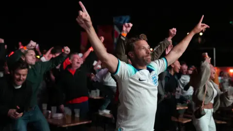 Getty Images A man wearing a white England shirt celebrating in front of a crowd. 