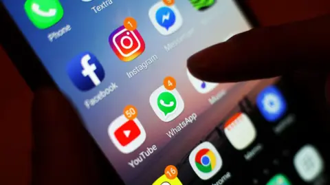 A clone up of a phone with various apps on it including Whatsapp, Youtube, Instagram and Facebook. There is a thumb over the music app. 