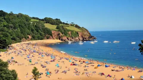 Getty Images An aerial view of Blackpool Sands in Devon shows hundreds of people enjoying a hot, summer's day. Several boats can be seen moored close to the beach. 