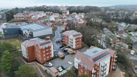 An aerial shot of a newly build housing development. With three blocks of flats in the foreground and new build houses further away.