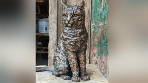 A bronze statue of a cat in a workshop