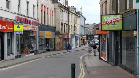 A quiet Arbroath High Street, with many empty units with For Sale or To Let Signs