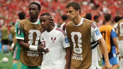 Qatar's Assim Madibo is comforted by team-mates after getting sent off in their World Cup game against Canada in 2026