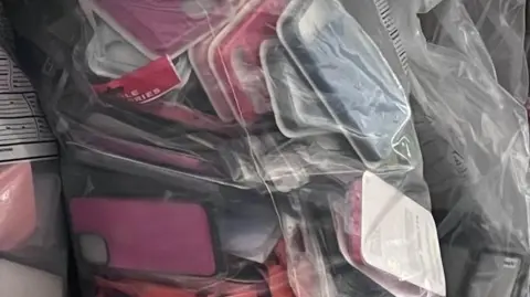 A clear plastic bag full of phone cases.
