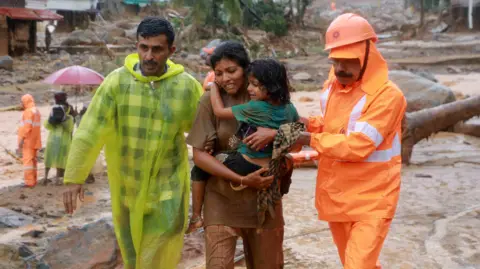 Reuters Rescuers help residents to move to a safer place, at a landslide site after multiple landslides in the hills, in Wayanad, in the southern state of Kerala, India, July 30, 2024.