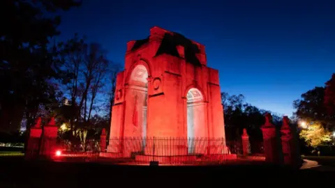 Leicester City Council A large war memorial at night, lit up by red floodlights