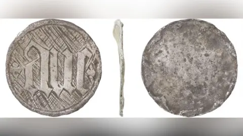 Andrew Willams/Norfolk County Council Three views of a silver disc, probably from a late medieval hollow reliquary or box pendant. On its front is etched the Latin word ave and a cross hatching design surrounds the word. Its back is plain and there is a thin side view