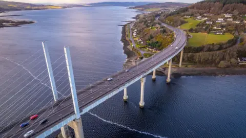 Getty Images An aerial view of the bridge. There are cars on the carriageway. The water that is visible is of the Beauly Firth, on the left, and Moray Firth to the right of the bridge. Underneath the crossing is the Kessock Channel.