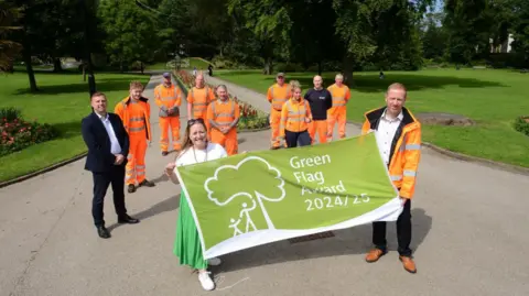 Sunderland City Council Park staff and council officials holding a green flag in Mowbray Park