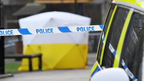 Reuters A police line with a white and yellow tent in the background. The tent covers the bench where Sergei and Yulia Skripal were found. 