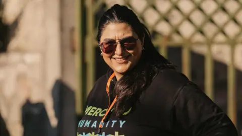 Sara Rashid wearing a black hoodie and sunglasses