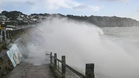 A wave crashing over a sea wall 