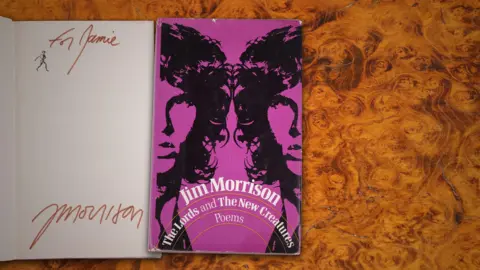 DAWSONS On the left is the first page of a book saying "To Jamie - Morrison". On the right is the front cover of the book with Jim Morrison on it