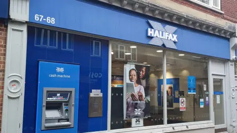 The front of a Halifax bank, with a cash machine on the left. 