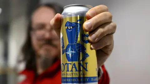 Finnish beer produced to commemorate country's entry into Nato is held up by a man.