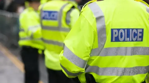 Three police officers in high visibility uniform.