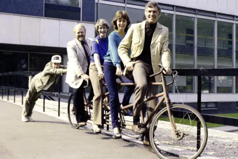 Pebble Mill At One presenters Donny MacLeod, Marian Foster, Marjorie Lofthouse, and Bob Langley on a pushbike being pushed by actorMarty Feldman,  