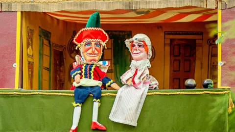 Two Punch and Judy dolls in a puppet house.