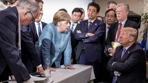 Bundesregierung/EPA  A handout photo made available by the German Government (Bundesregierung) on 09 June 2018 shows French President Emmanuel Macron (3-L, partially hidden), German Chancellor Angela Merkel (C-L) and Japan"s Prime Minister Shinzo Abe (C-R) speaking to US Presidend Donald J. Trump (R, seated) during the second day of the G7 meeting in Charlevoix, Canada