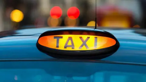 Getty A close up of a bright red taxi sign on top of a vehicle