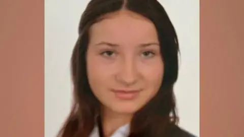 Family handout A teenage girl with long brown hair looks at the camera. She is wearing a white shirt, a navy and white striped tie and a navy blazer.