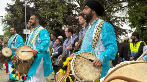 Men holding drums wearing traditional south Asian clothes 