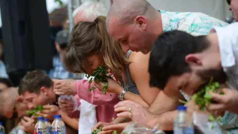 Alresford Watercress Festival A mix of men and women pushing watercress into their mouths.
