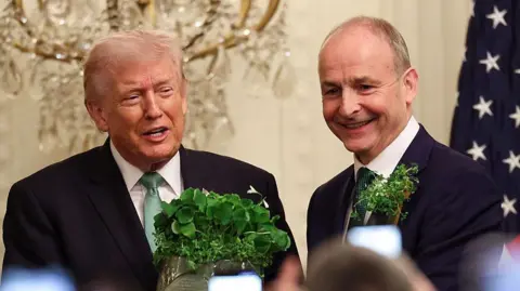 President Donald Trump receives a bowl of shamrocks from Taoiseach of Ireland Micheál Martin (R) during a St. Patrick’s Day event in the East Room of the White House on March 17, 2026 in Washington, DC.