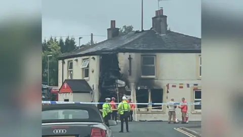 PaulDumville Police and emergency services look on at the damage to the White Lion pub 